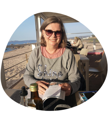 Karin, in einer Strandbar in einem Reisefuehrer blaetternd